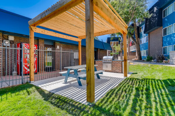 Sky at Bear Creek apartments grill area with picnic table and vending machine under pergola