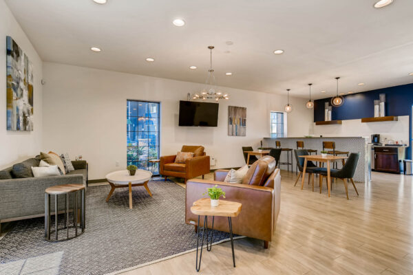 Sky at Bear Creek apartments community kitchen and lounge with tables and chairs, barstools, tv, and coffee bar