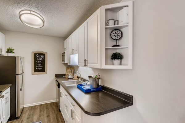 Sky at Bear Creek apartments kitchen with wood-style flooring, white cabinets, and stainless steel appliances