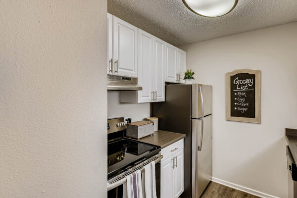 Sky at Bear Creek apartments kitchen with wood-style flooring, white cabinets, and stainless steel appliances