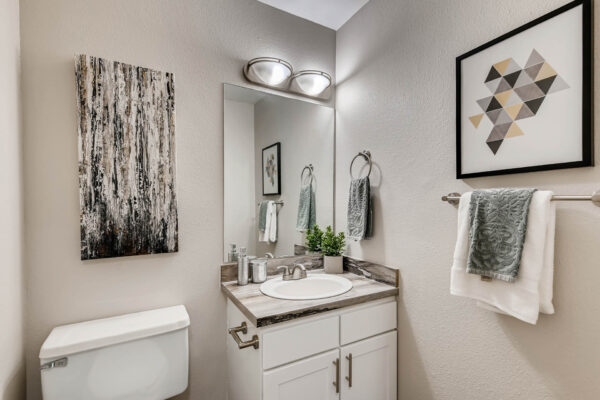 Sunset Peak apartments bathroom featuring white cabinets, silver hardware, marble like countertops, and a shower tub with white tile