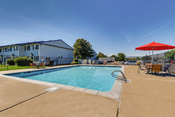 Sunset Peak apartments outdoor scene featuring community pool and outdoor seating areas with red umbrellas