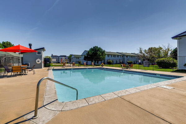 Sunset Peak apartments outdoor scene featuring community pool and outdoor seating areas with red umbrellas