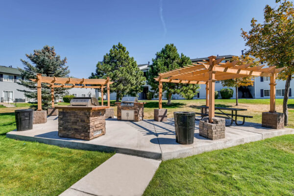 Sunset Peak apartments outdoor grassy space with two wood pergolas and 2 barbecue pits