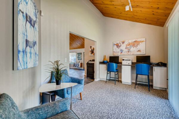 Sunset Peak apartments indoor community space with lounge area and two work spaces with computers