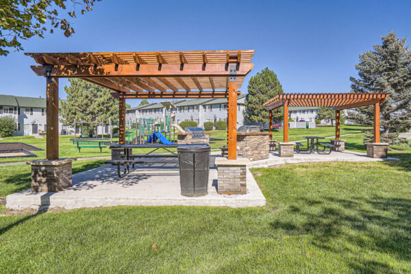 Sunset Peak apartments outdoor grassy space with two wood pergolas and 2 barbecue pits