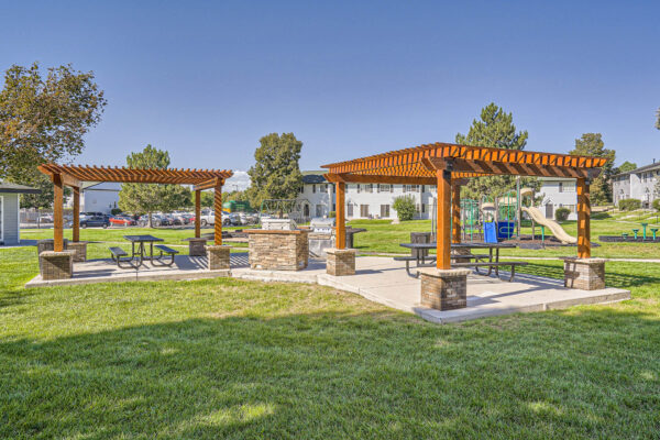 Sunset Peak apartments outdoor grassy space with two wood pergolas and 2 barbecue pits