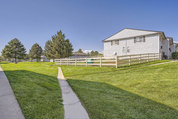 Sunset Peak apartments light blue apartments with dark shutters, green lawns, and fenced in dog park