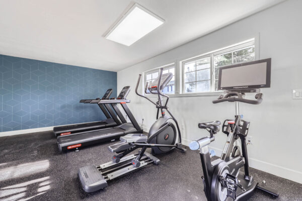 Sunset Peak apartments indoor fitness center featuring two treadmills, an elliptical, and a spin bike