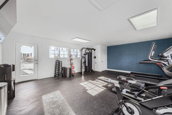 Sunset Peak apartments indoor fitness center featuring a multi-functional weight machine, dumbbells, resistance bands, and exercise balls