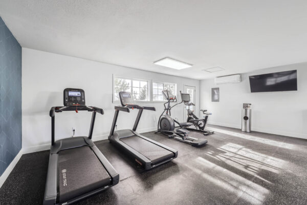 Sunset Peak apartments indoor fitness center featuring two treadmills, an elliptical, and a spin bike
