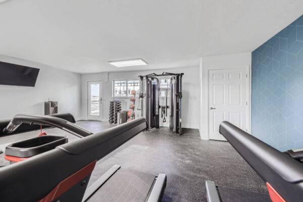 Sunset Peak apartments indoor fitness center featuring a multi-functional weight machine, dumbbells, resistance bands, and exercise balls