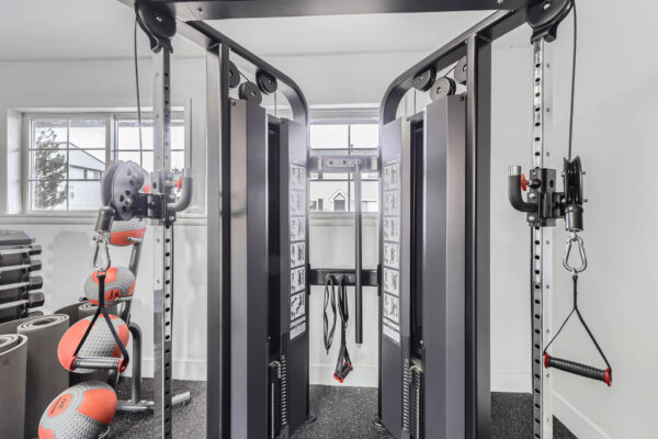 Sunset Peak apartments indoor fitness center featuring a multi-functional weight machine, dumbbells, resistance bands, and exercise balls