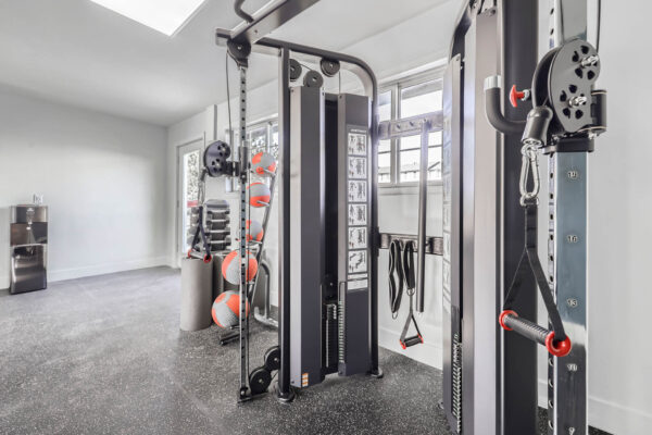 Sunset Peak apartments indoor fitness center featuring a multi-functional weight machine, dumbbells, resistance bands, and exercise balls