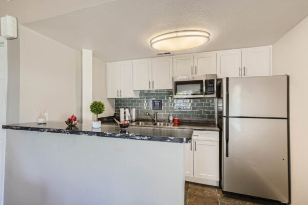Sunset Peak apartments shared community kitchen with white cabinets, a sink, microwave, and refridgerator