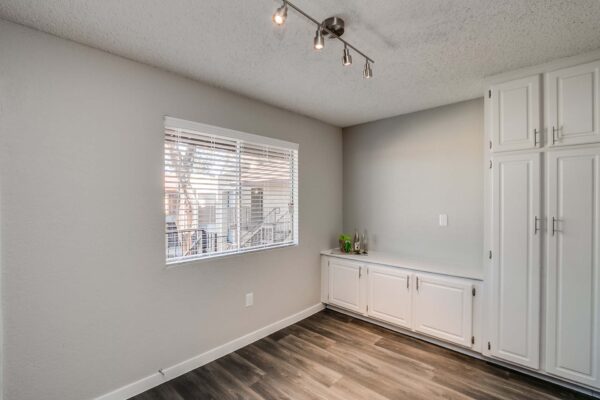 Tempe Vista apartment dining area with wood style floor, built in cupboards, and large window.