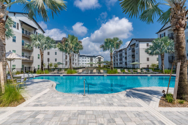 The Avery apartments pool area with stone paver patio and palm trees.