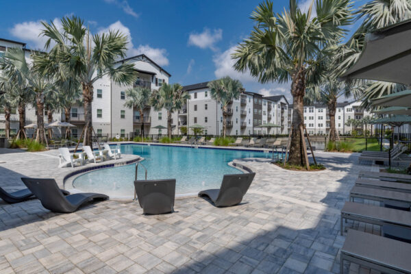 The Avery apartments pool area with lounge chairs and palm trees.