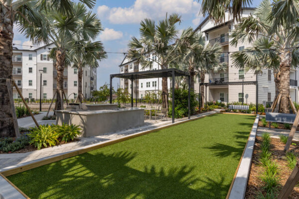 The Avery apartments outdoor lounge with turf lawn, BBQ grill, and pergolas.