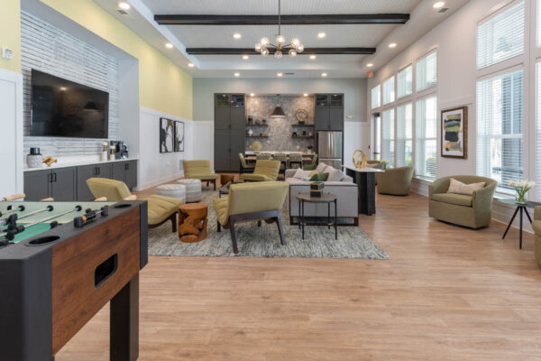 The Avery apartments lounge with foosball table, plush seating, and TV.