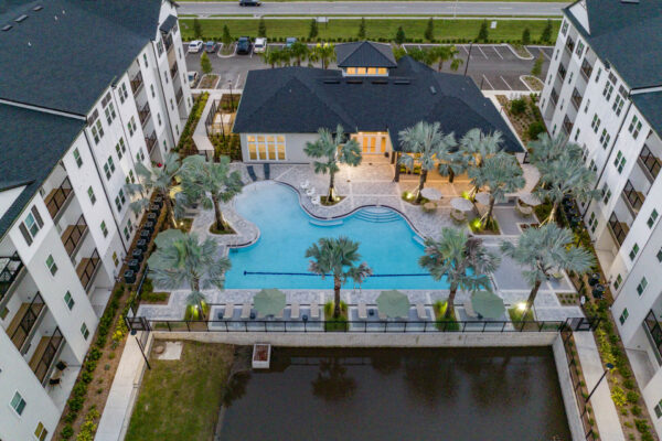 The Avery apartments pool area with lounge chairs, umbrellas, and palm trees.
