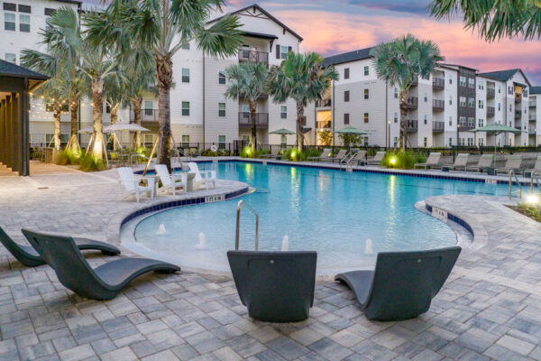 The Avery apartments pool area with lounge chairs and palm trees.