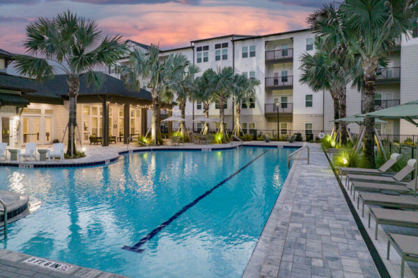 The Avery apartments pool area with lounge chairs and palm trees.