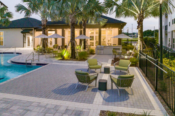 The Avery apartments pool area with lounge chairs, umbrellas, and palm trees.