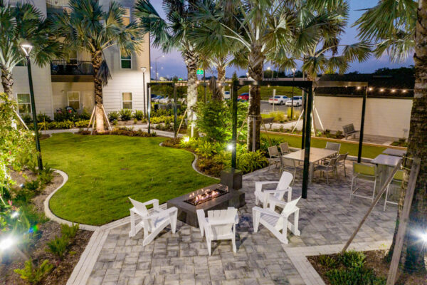 The Avery apartments outdoor lounge with chairs, fire pit, and lush lawn.