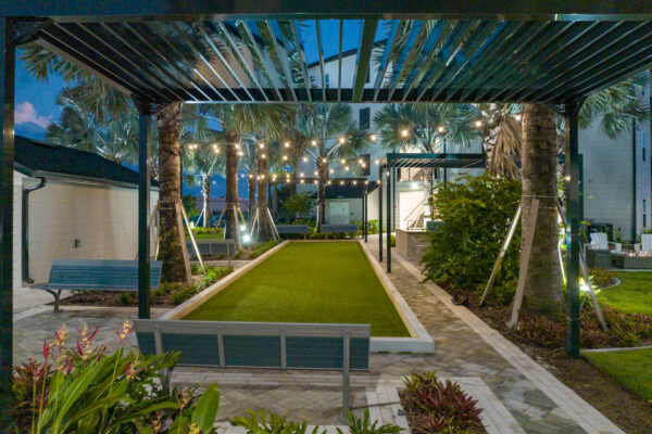 The Avery apartments outdoor lounge with benches, pergolas, and turf lawn.
