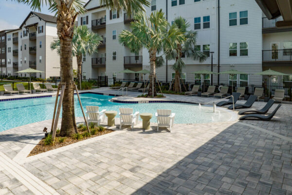 The Avery apartments pool area with lounge chairs and palm trees.
