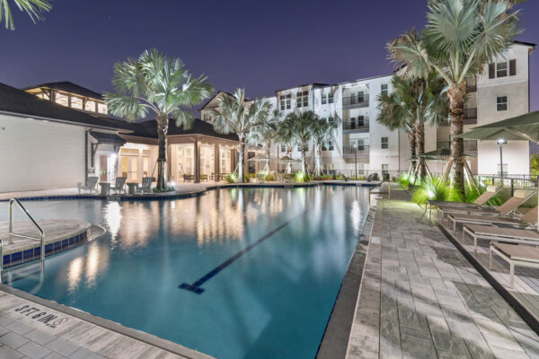 The Avery apartments pool area with lounge chairs and palm trees.