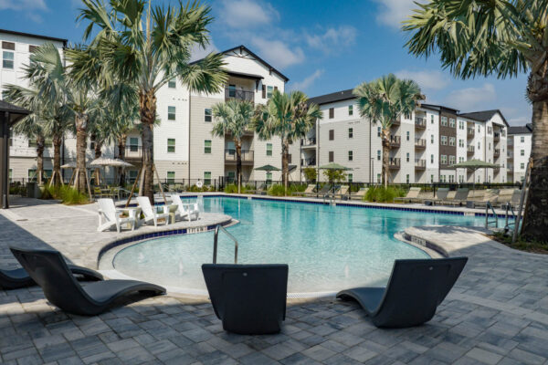 The Avery apartments pool area with lounge chairs and palm trees.