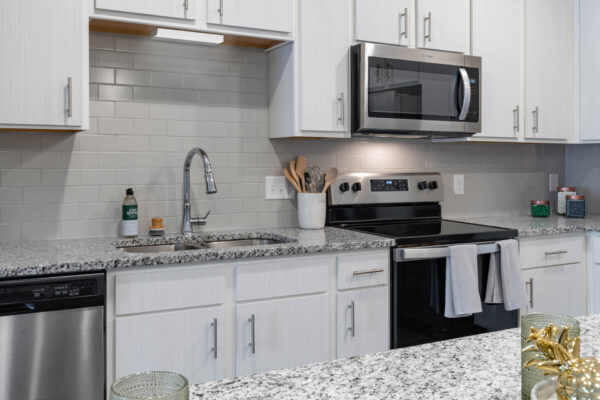 The Avery apartment kitchen with white cabinets, stone counters, and stainless steel appliances.