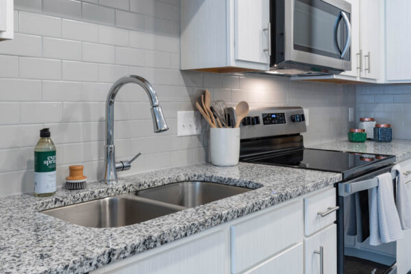 The Avery apartment kitchen with white cabinets, stone counters, and stainless steel appliances.