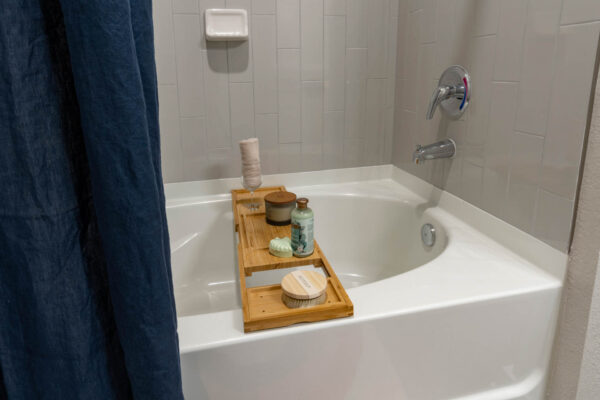 The Avery apartment bathroom with tiled shower tub and bath supplies.