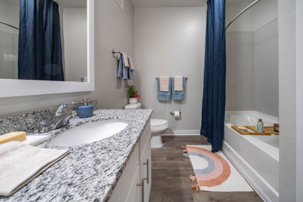 The Avery apartment bathroom with tiled shower tub and bath supplies.