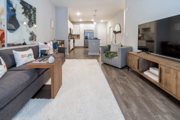 The Avery apartment living room with wood style floor, plush seating, large artwork, and TV.