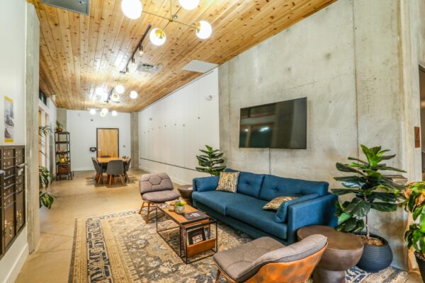 The Economist apartments lounge with plush seating, wall mounted TV, and mailboxes.
