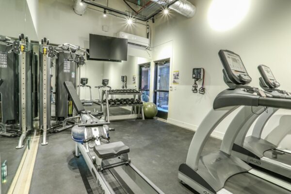 The Economist apartments fitness center with cardio machines and weight equipment.