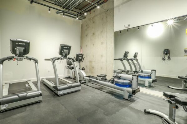 The Economist apartments fitness center with cardio machines and weight equipment.