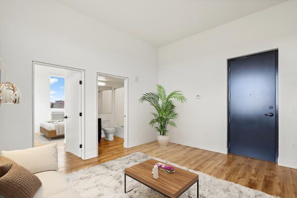 The Economist apartment living room with wood style floor, plush seating, and potted plant.
