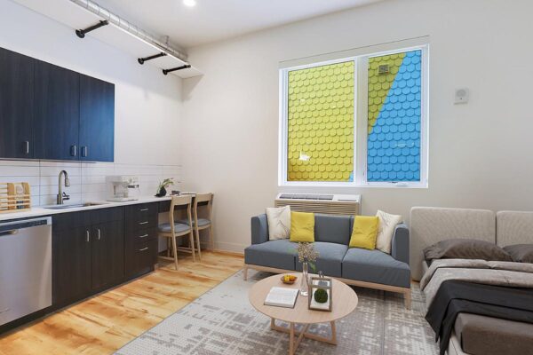 The Economist apartment living area with plush seating, modern kitchen, and large window.