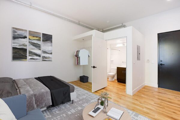 The Economist apartment living area with plush seating, bed, closet, and bathroom.