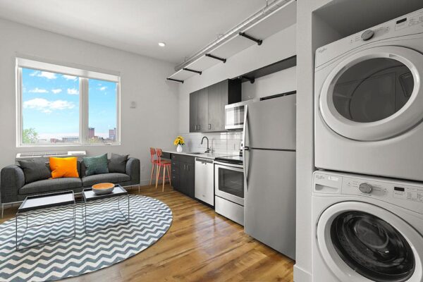 The Economist apartment living area with plush seating, modern kitchen, and stacked washer dryer.