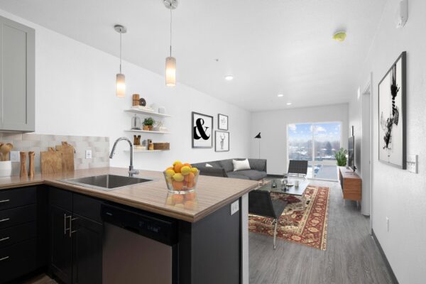 The Overland apartment living room with wood style floor, plush seating, and large window.