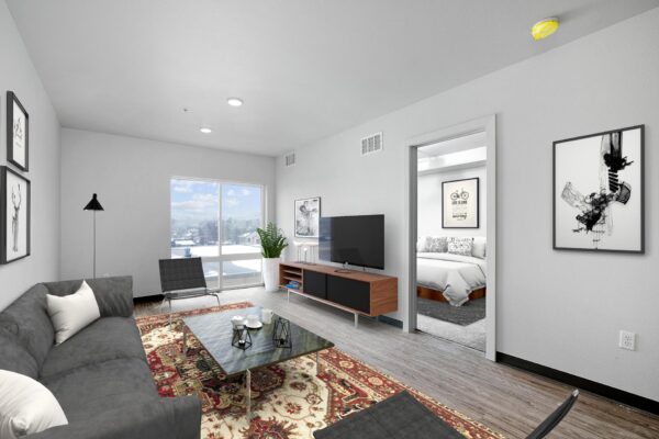 The Overland apartment living area with woods style floor, plush seating, and large windows.