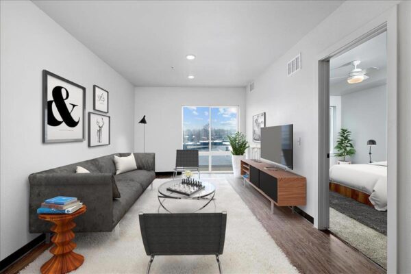 The Overland apartment living room with plush seating, TV, wall art, and large windows.