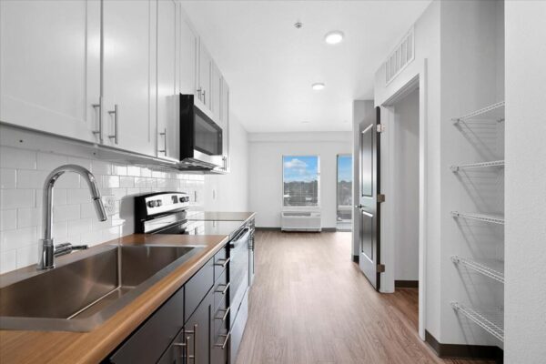 The Overland apartment kitchen with two tone cabinets and stainless steel appliances.