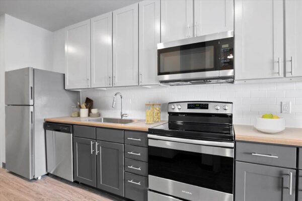 The Overland apartment kitchen with two tone cabinets and stainless steel appliances.